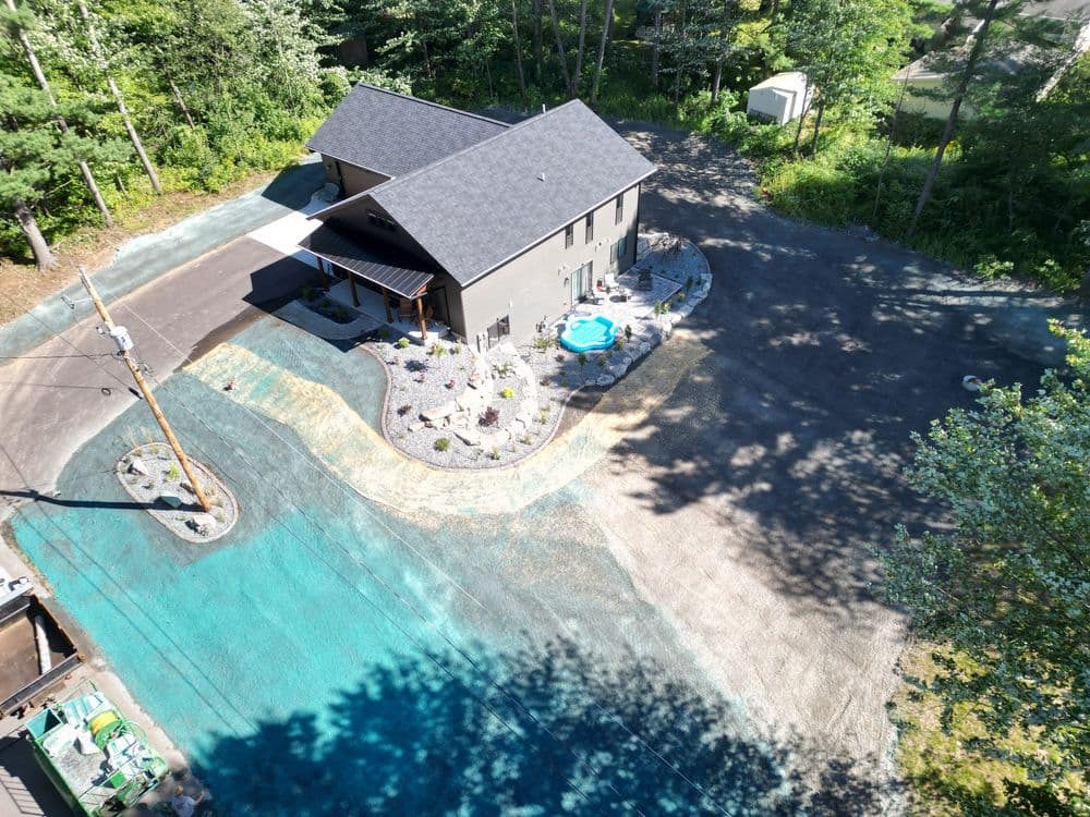 Aerial view of a modern house with a pool surrounded by landscaped yard and trees.